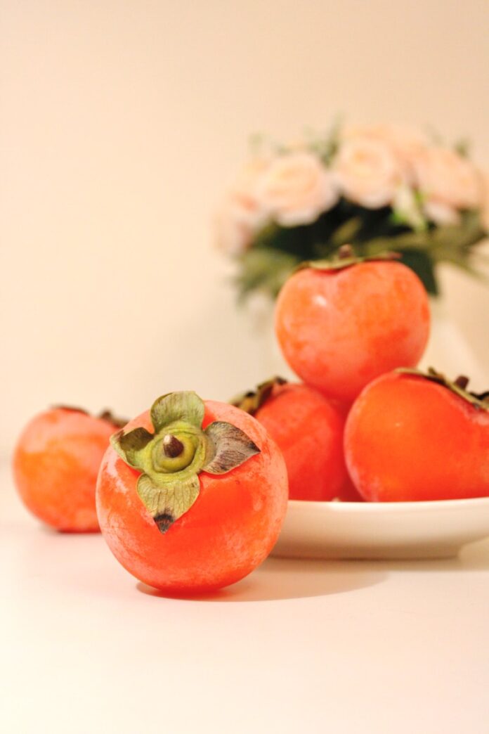 a white plate topped with tomatoes next to a vase of flowers