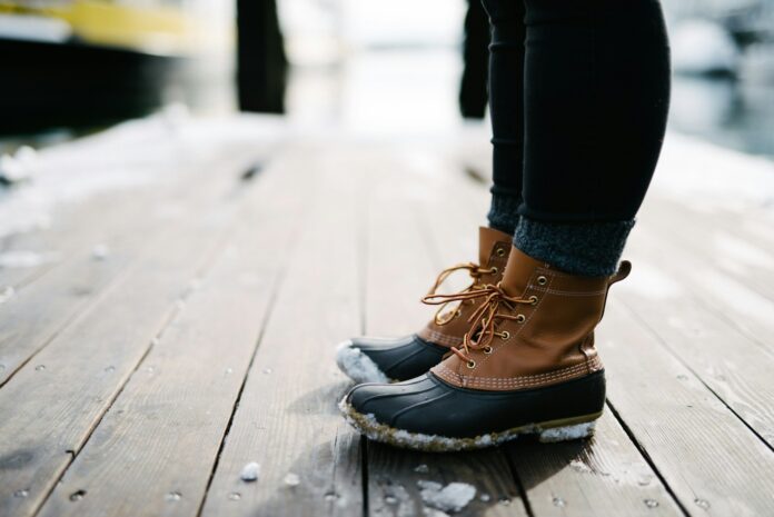 Photo by Robert Nelson person wearing brown-and-black leather duck boots standing on brown wooden dock