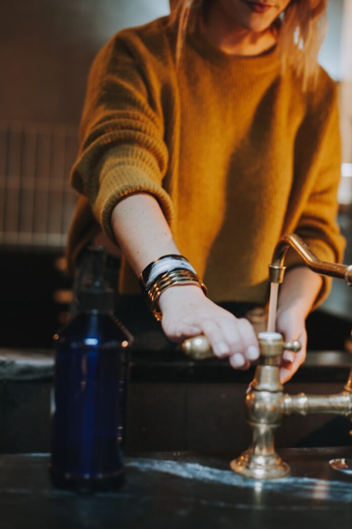 Photo by Christin Hume photo of woman holding brass-colored faucet