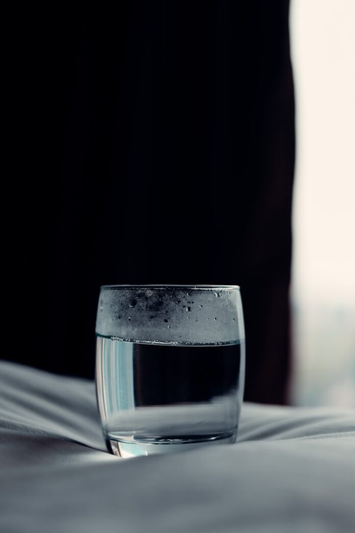Photo by BenMoses M a glass of water sitting on top of a bed