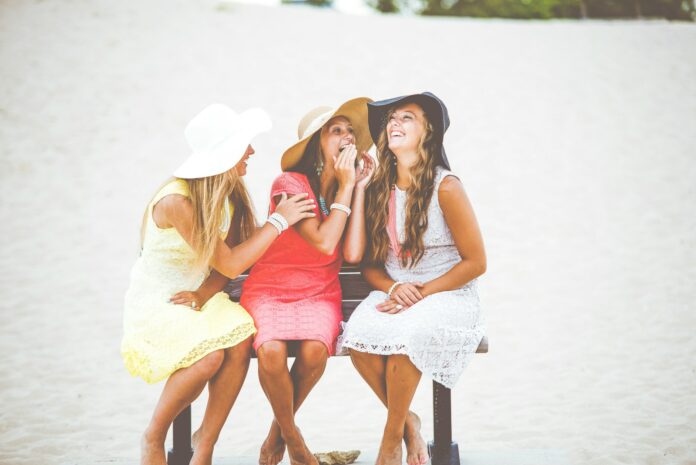 Photo by Ben White three women sitting on brown wooden bench