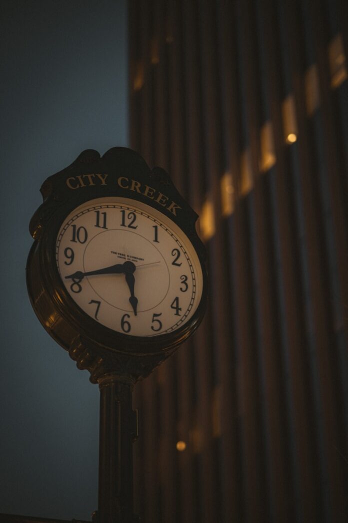 Photo by Isaac Mitchell a clock on a pole in front of a building