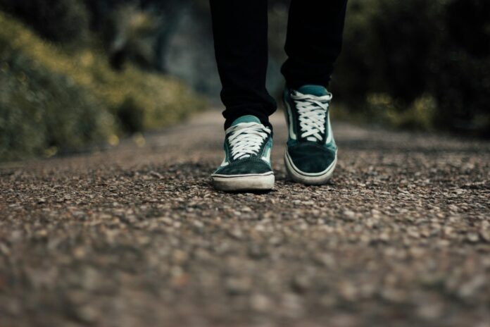 Photo by Youcef Chenzer a person standing on a gravel road with their shoes on