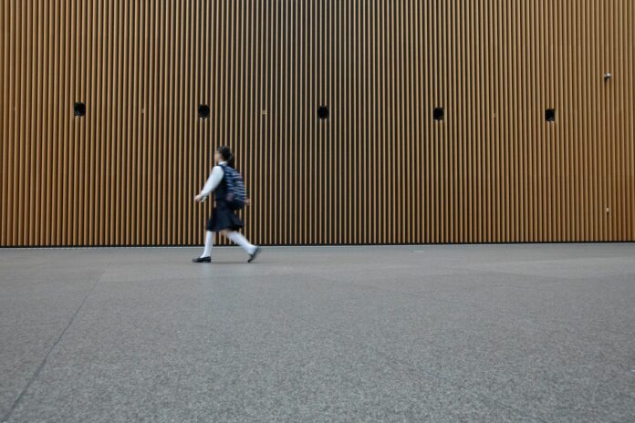 Photo by Christoph Theisinger woman in uniform walkin on gray concrete pavement during daytime